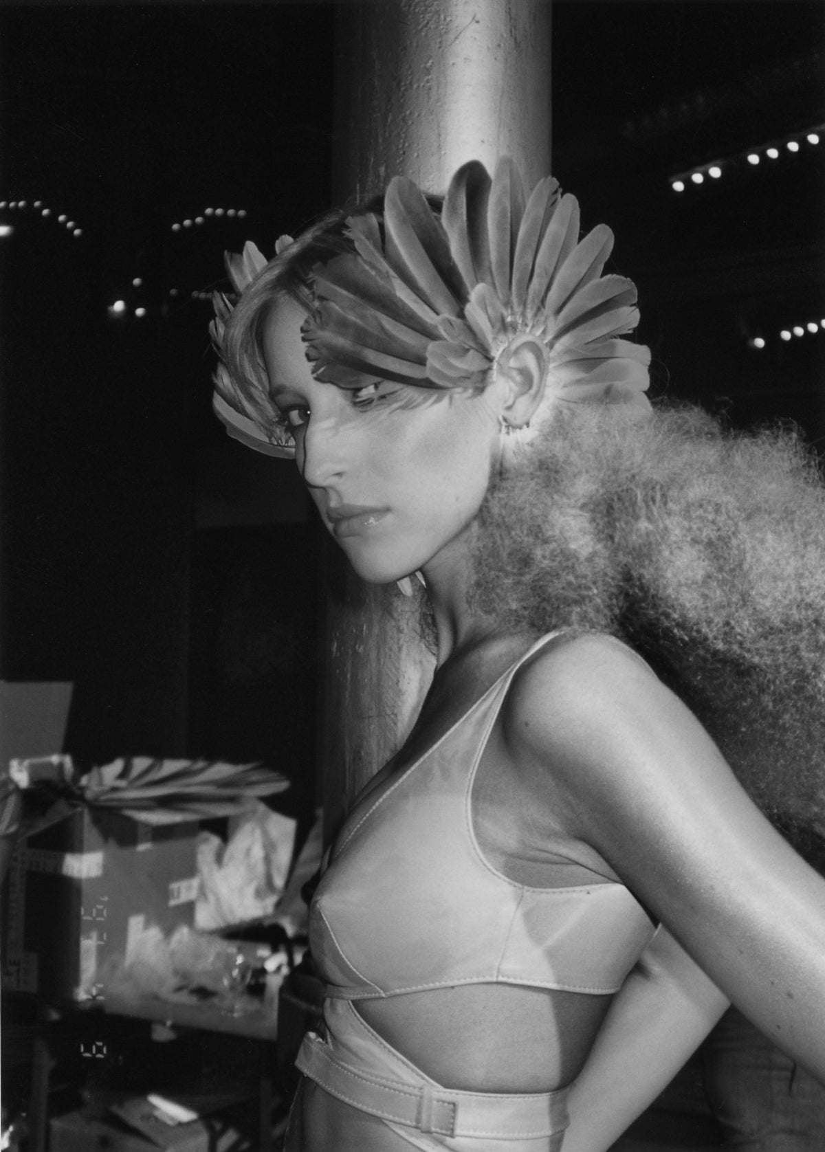 Backstage portrait from Alexander McQueen's Irere, showing a model with feathered face adornment