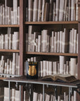 Trudon candle beside an open book in a historic library