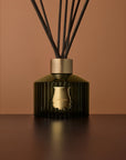 Trudon classic green-glass diffuser against a terracotta background