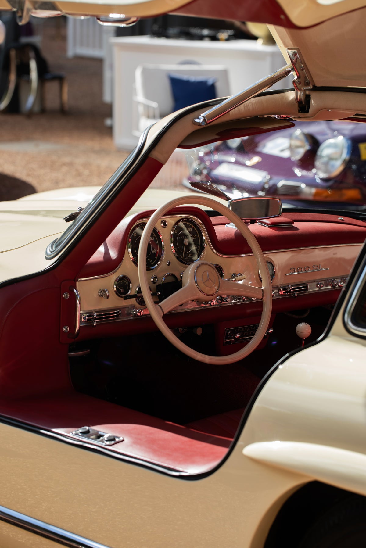 Red dashboard and cream steering wheel viewed through the open door of a silver car.