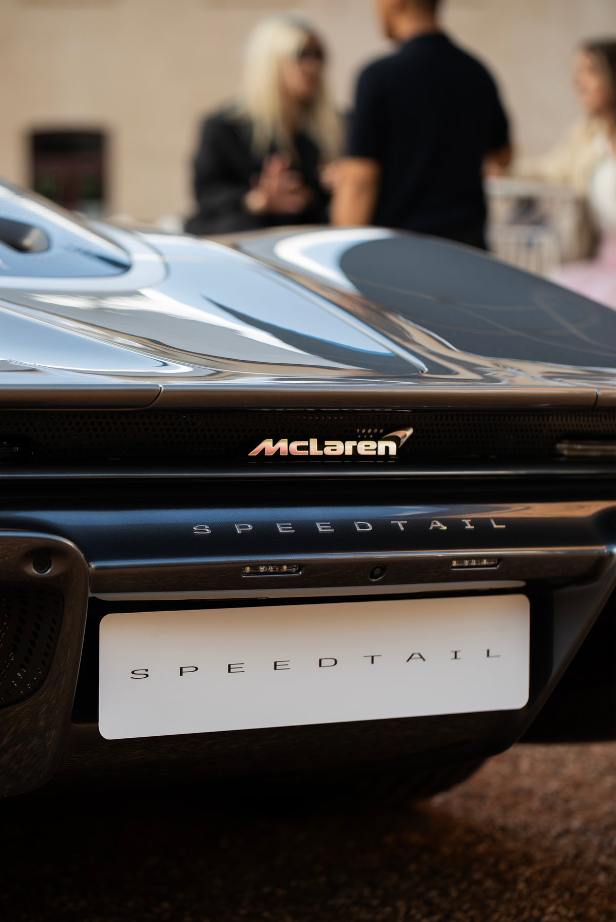 Close view of a dark sports car's rear bodywork and narrow black grille.