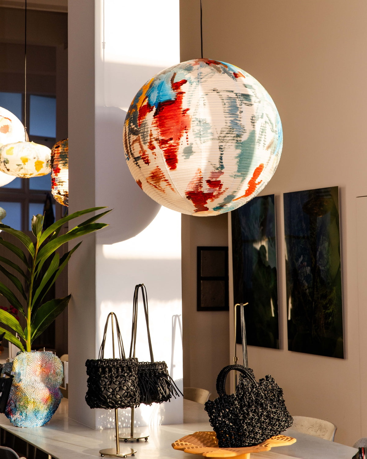 Black braided A-ESQUE bags displayed beneath a colourful spherical light at HŌLUS BŌLUS