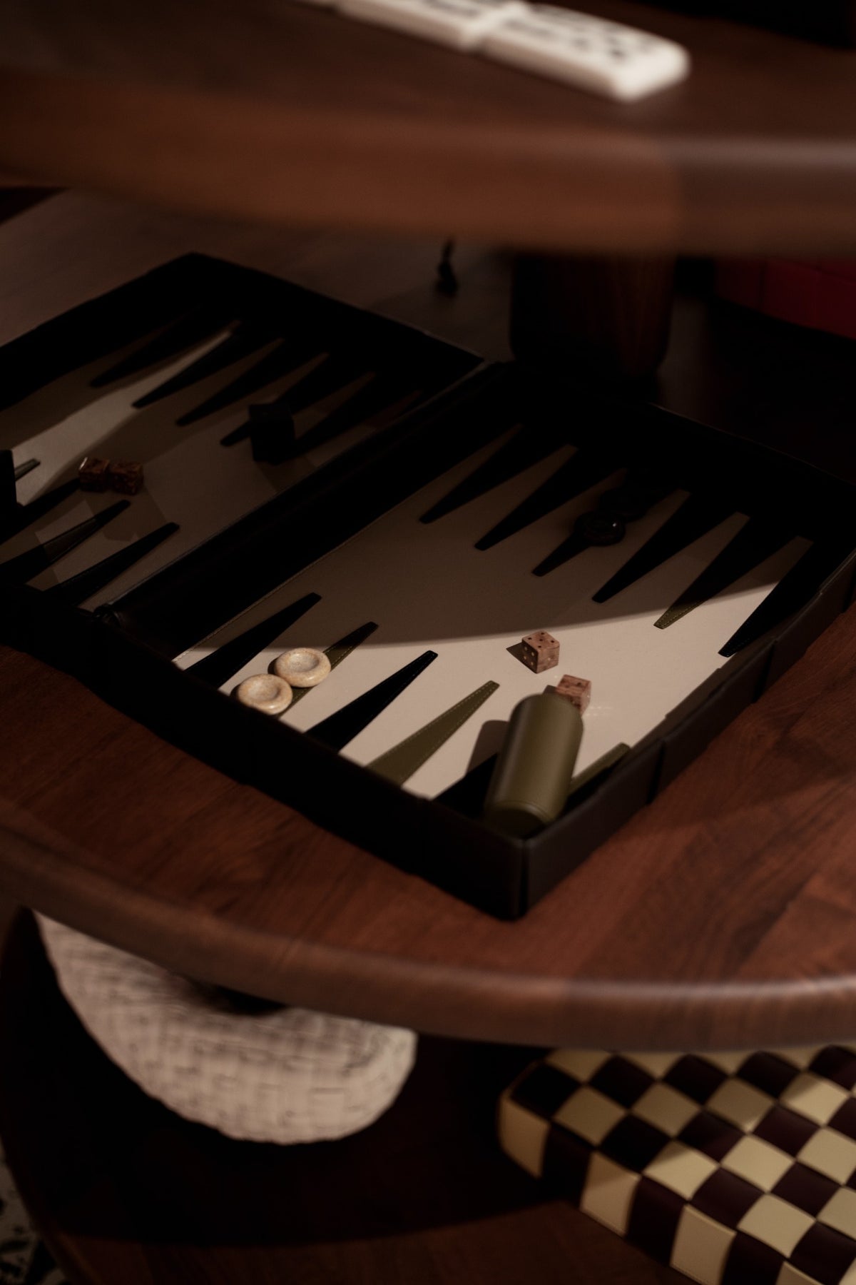 A backgammon set on a wooden table at Bottega Veneta, with woven objects below