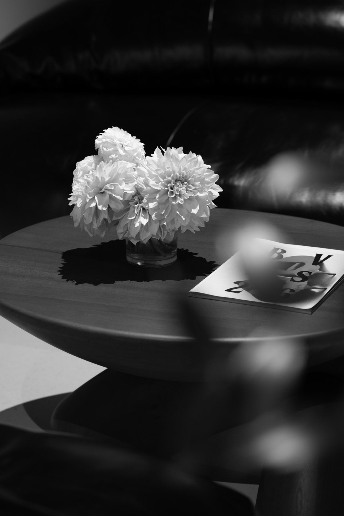White flowers beside a Bottega Veneta booklet, photographed in black and white