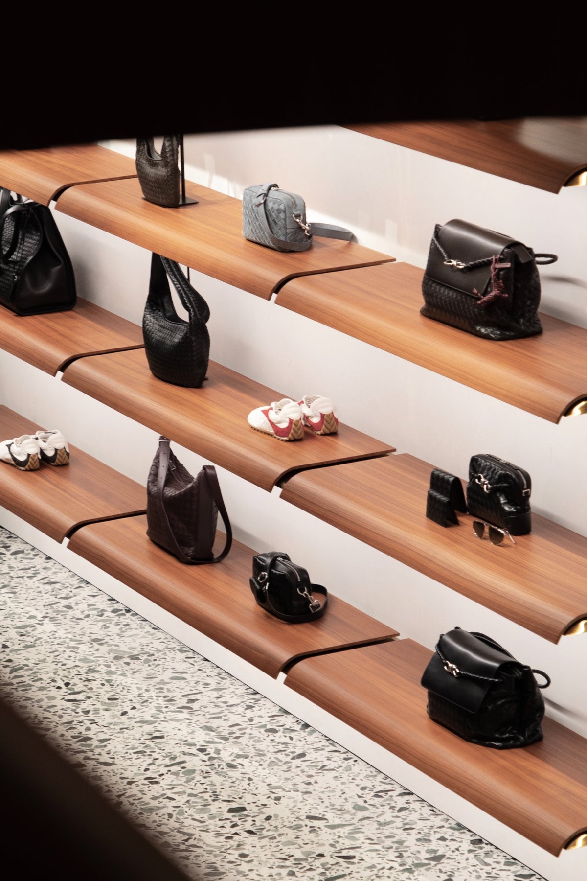 Bags and shoes displayed on wooden shelves at Bottega Veneta