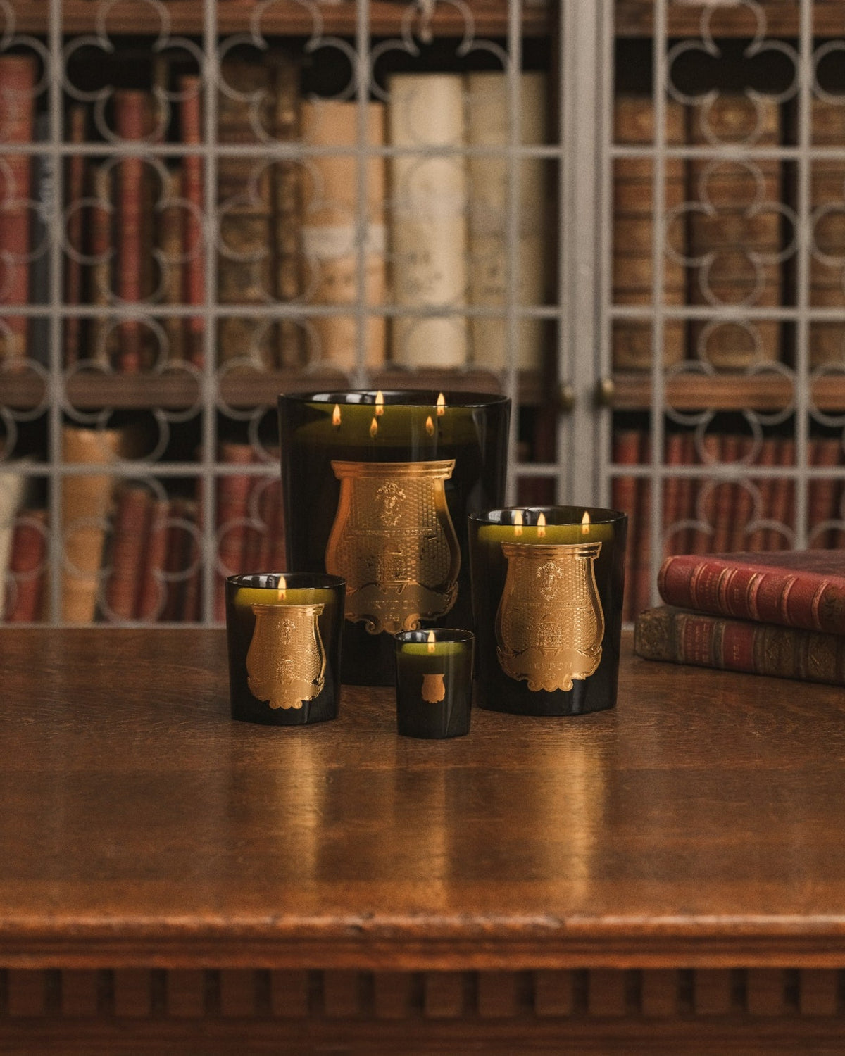 Four sizes of Trudon classic green candles arranged in a library