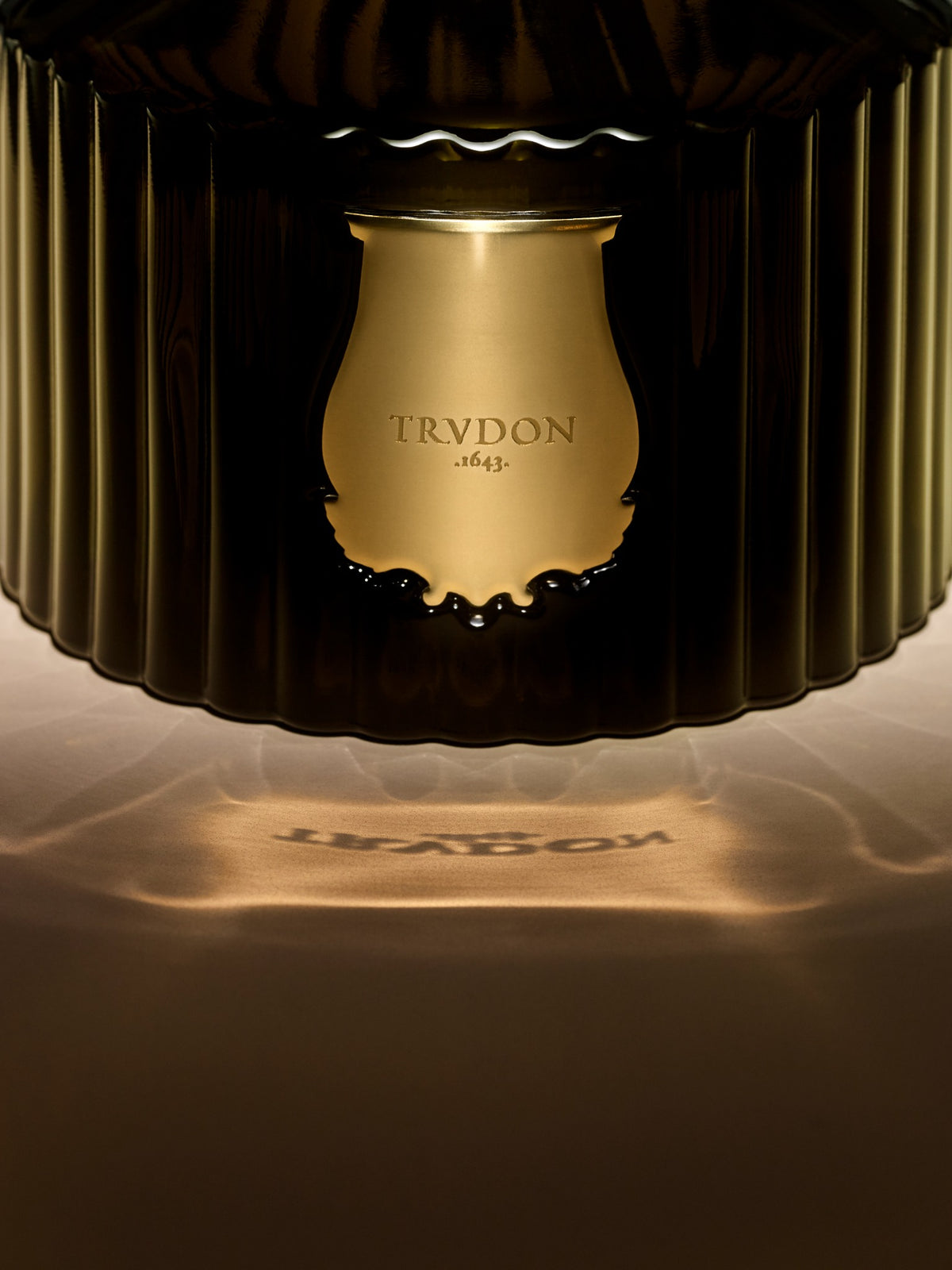 Close-up of the Trudon diffuser's fluted green glass and gold emblem